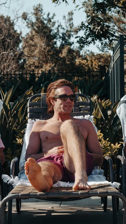 Hombre con gafas de sol sonriendo en la piscina Stock Photo