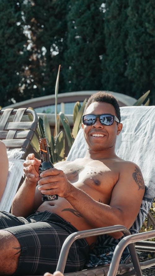 Man Wearing Sunglasses while Holding Beer Bottle