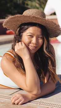 Woman in a sun hat relaxing by the pool on a sunny day.
