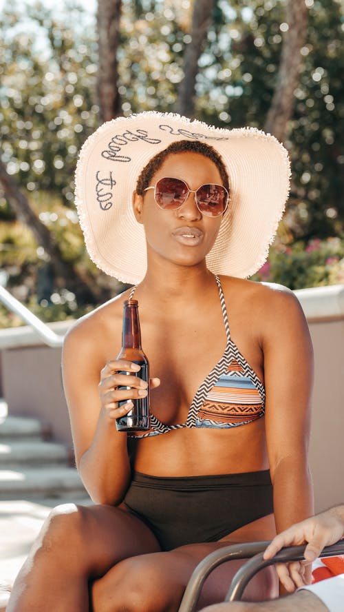 Free Woman Wearing a White Sun Hat Holding Beer Bottle Stock Photo