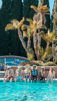 A diverse group of friends sitting poolside under sunny skies, enjoying summer together.