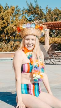 A woman enjoying a summer poolside party, wearing a colorful bikini and tropical accessories, exuding joy.