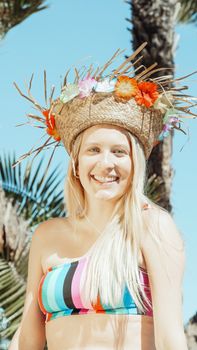 Blonde woman enjoying a sunny day in a straw hat and colorful bikini, radiating happiness.