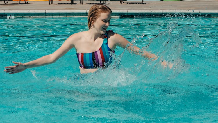 Woman Having Fun Splashing Water In The Swimming Pool