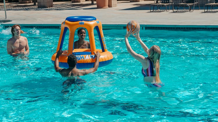 People Having Fun Playing Basketball In The Swimming Pool