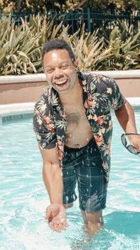 Smiling man enjoying a splash in the pool at a summer resort.