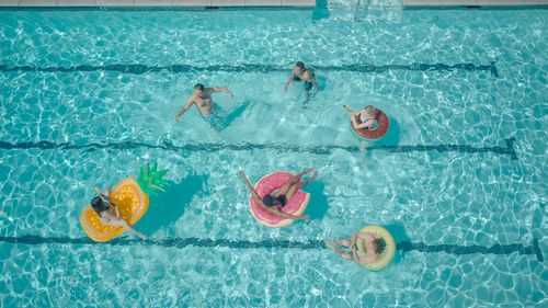 Free A vibrant top view of friends having fun at a pool party with colorful floats. Stock Photo