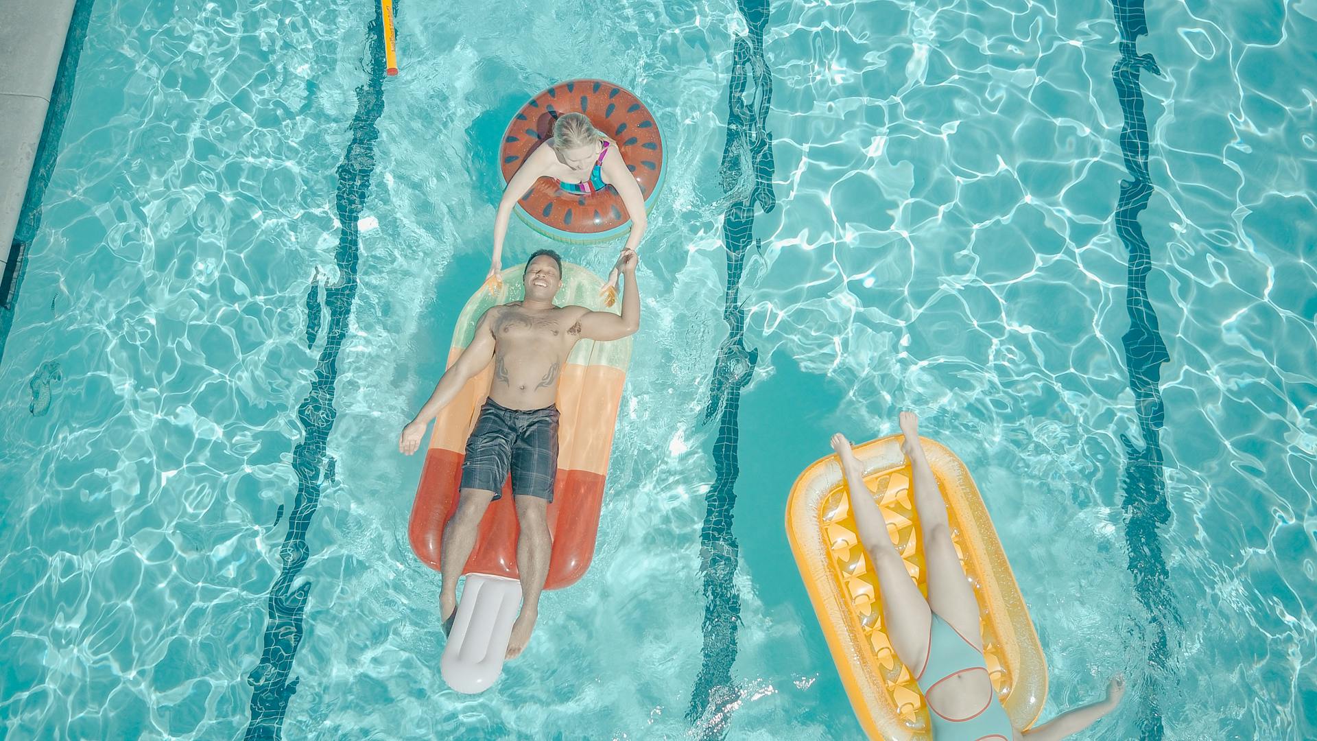 Enjoying a summer pool party with friends on colorful floats, capturing fun and relaxation.