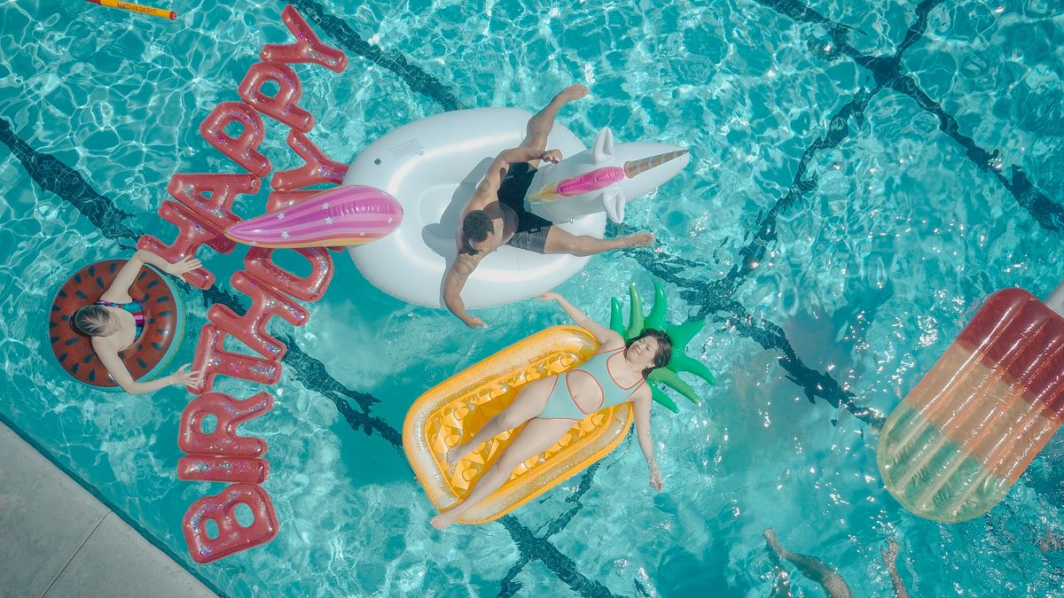 A top view of a lively pool party with floats and 'Happy Birthday' sign, capturing fun and relaxation. Stock Photo.