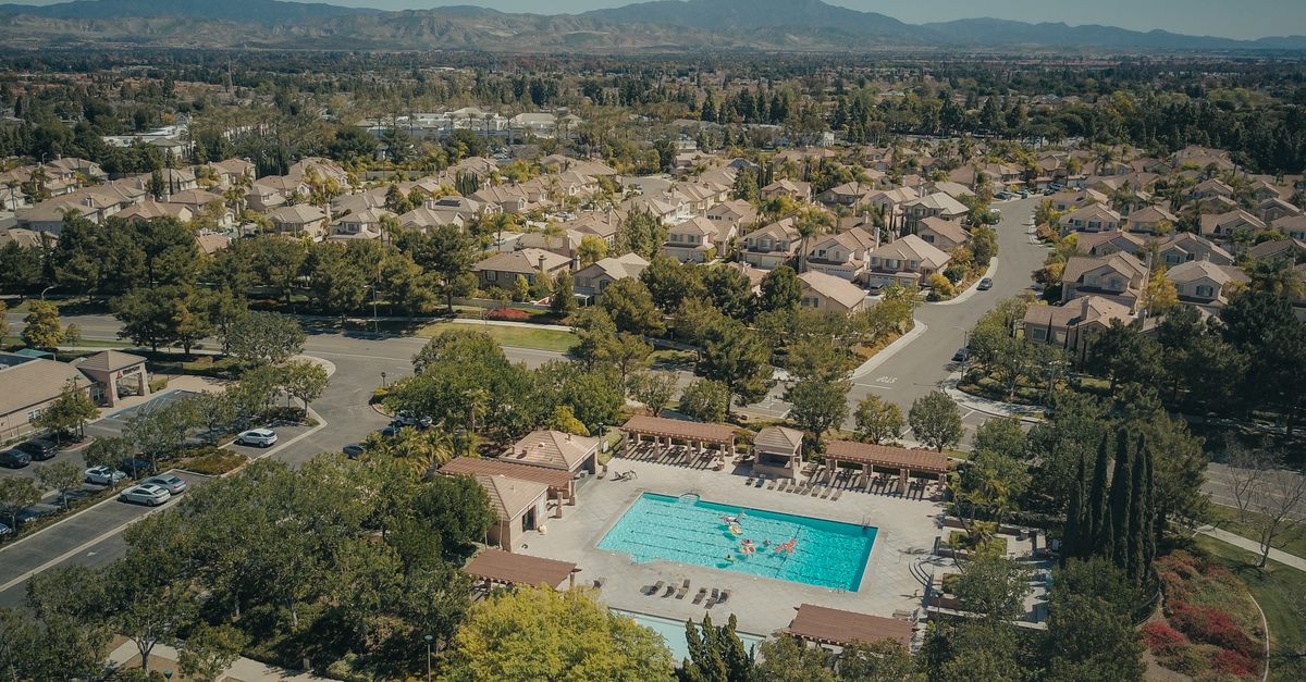 Aerial shot of a suburban neighborhood featuring a community swimming pool on a sunny day.