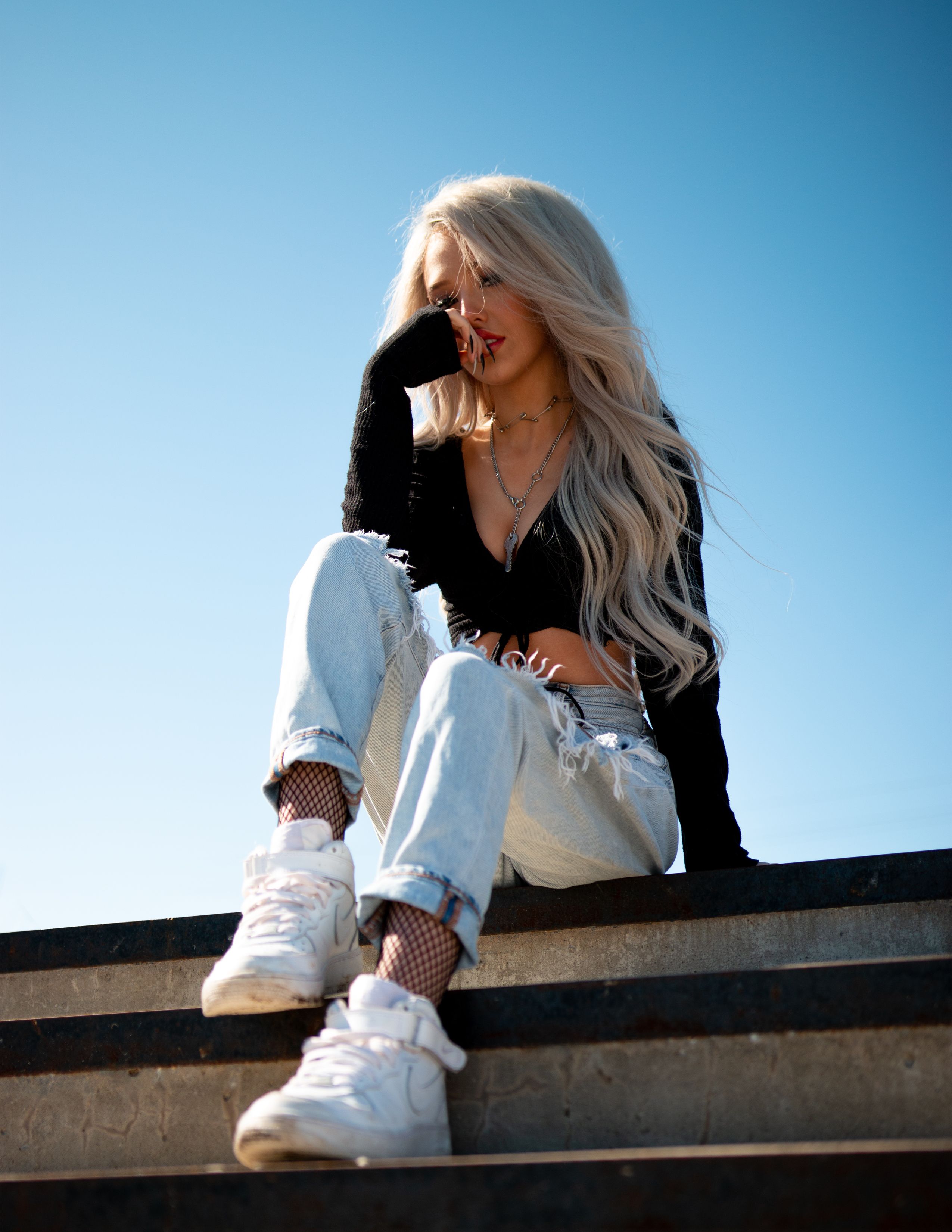 Stylish blonde woman sitting on stairs, casual fashion, sunny day, Toronto.