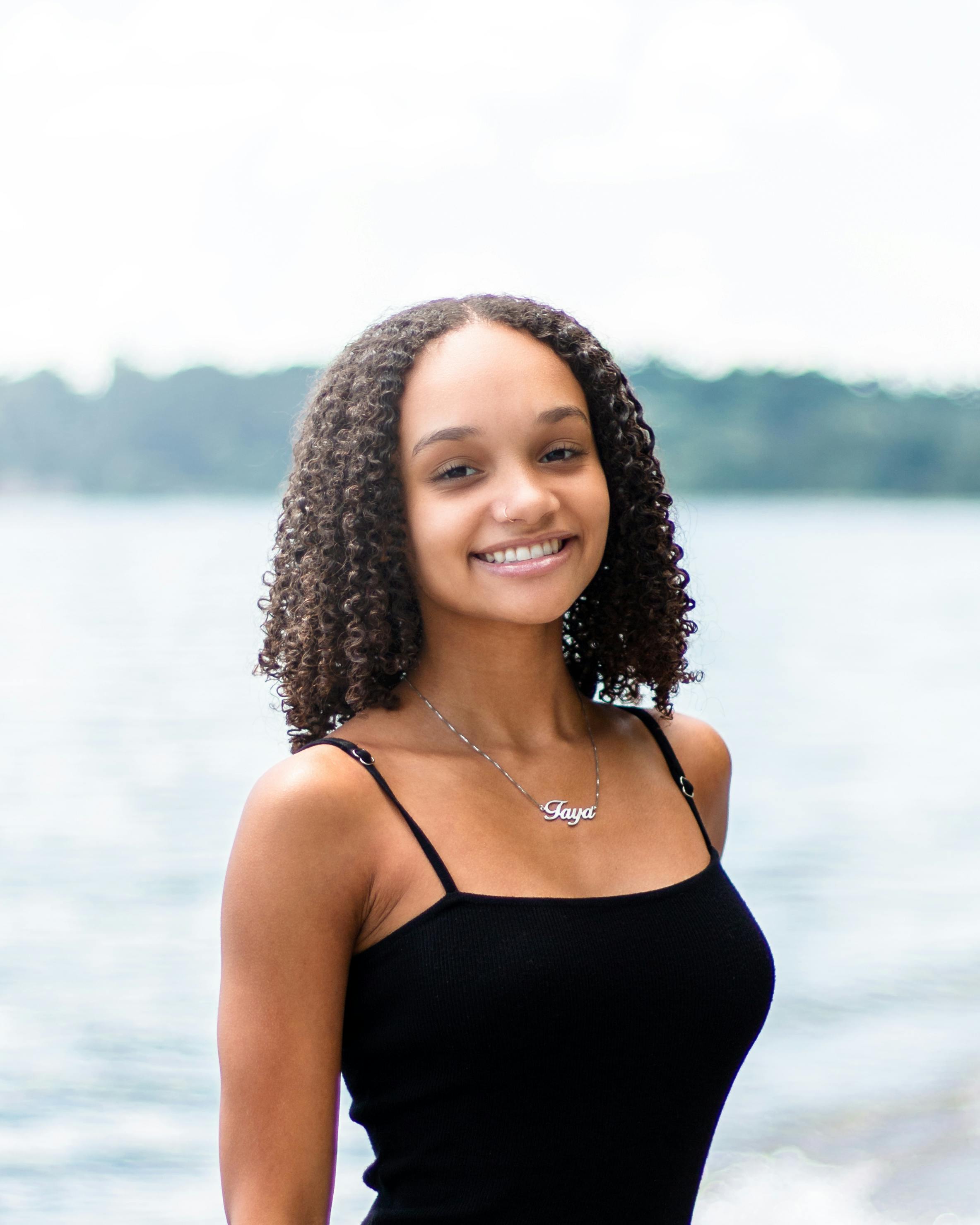 Young woman with curly hair smiling by a lake in Toronto, Canada.