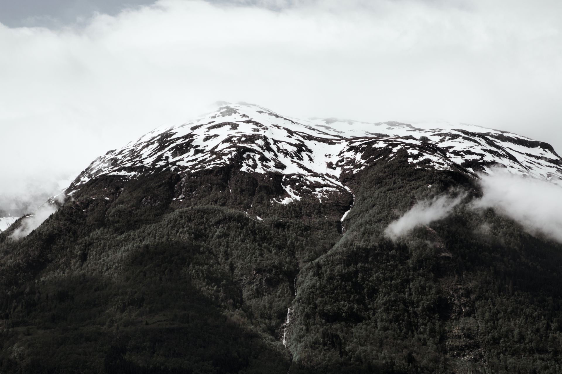 A breathtaking aerial view of a snow-capped mountain surrounded by mist in Norway's winter landscape.