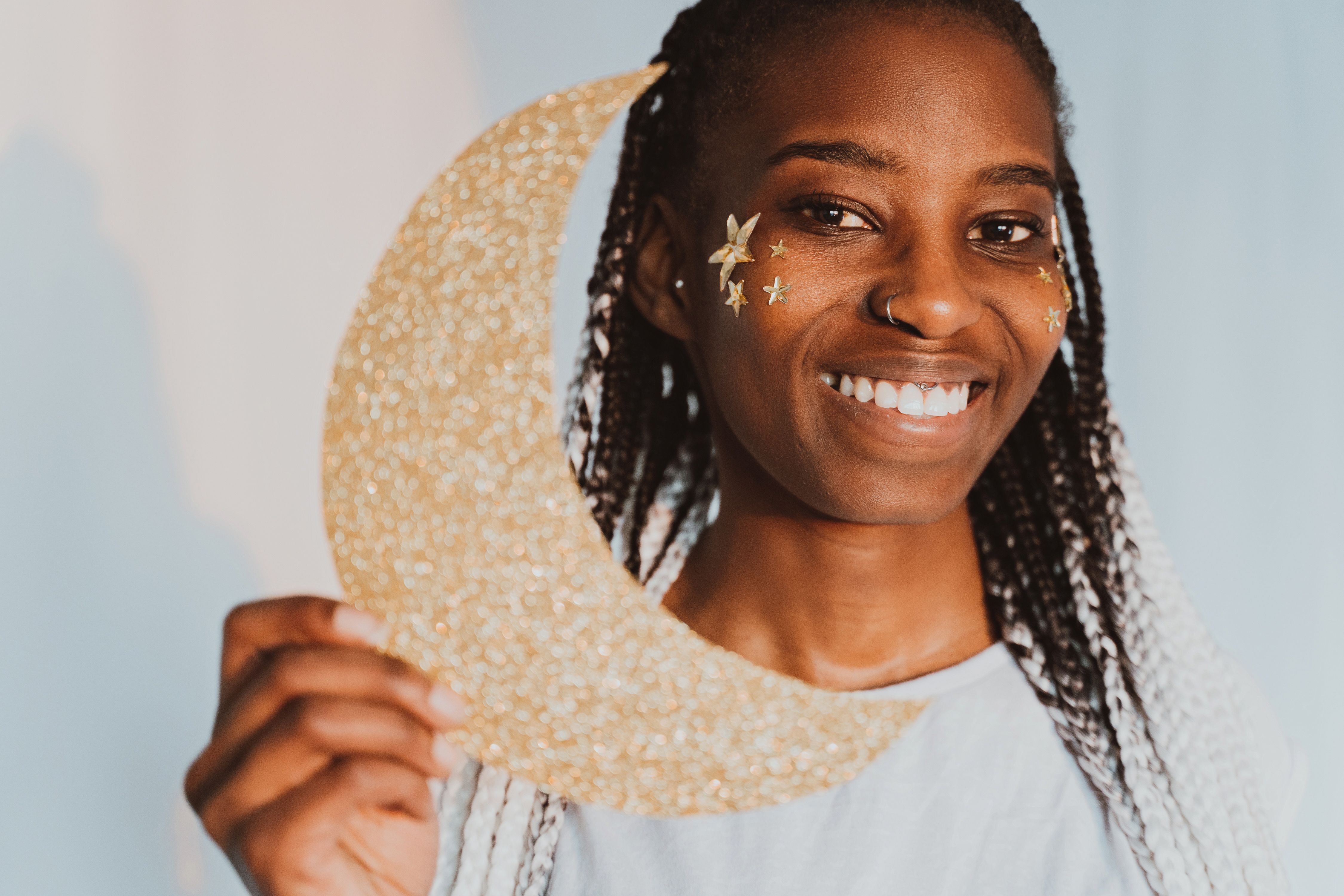 Portrait of a joyful woman holding a glittery crescent moon, showcasing a creative and whimsical style.