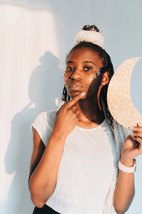 Woman in White Crew Neck Shirt Holding Gold Half Moon Ornament