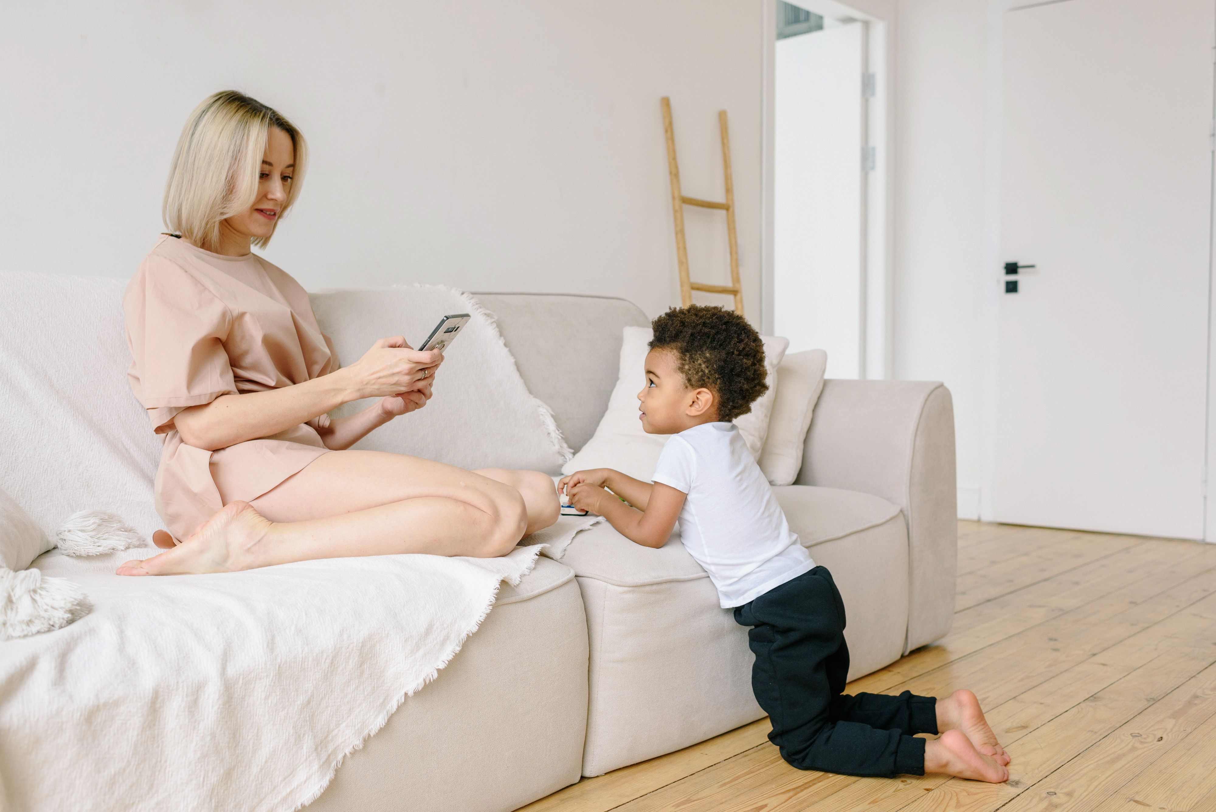 A mother and her son enjoying a relaxing moment indoors with a phone on a comfy sofa.