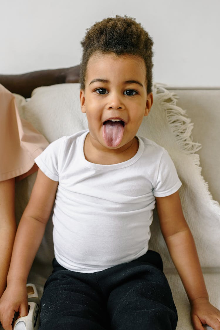 Child In White Crew Neck Shirt Sticking Out Tongue 