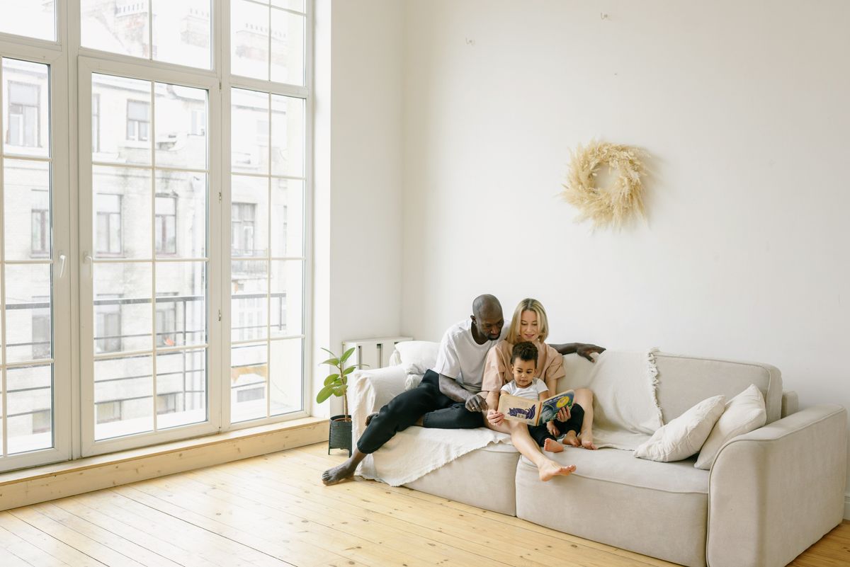A family reading together on a bright living-room sofa