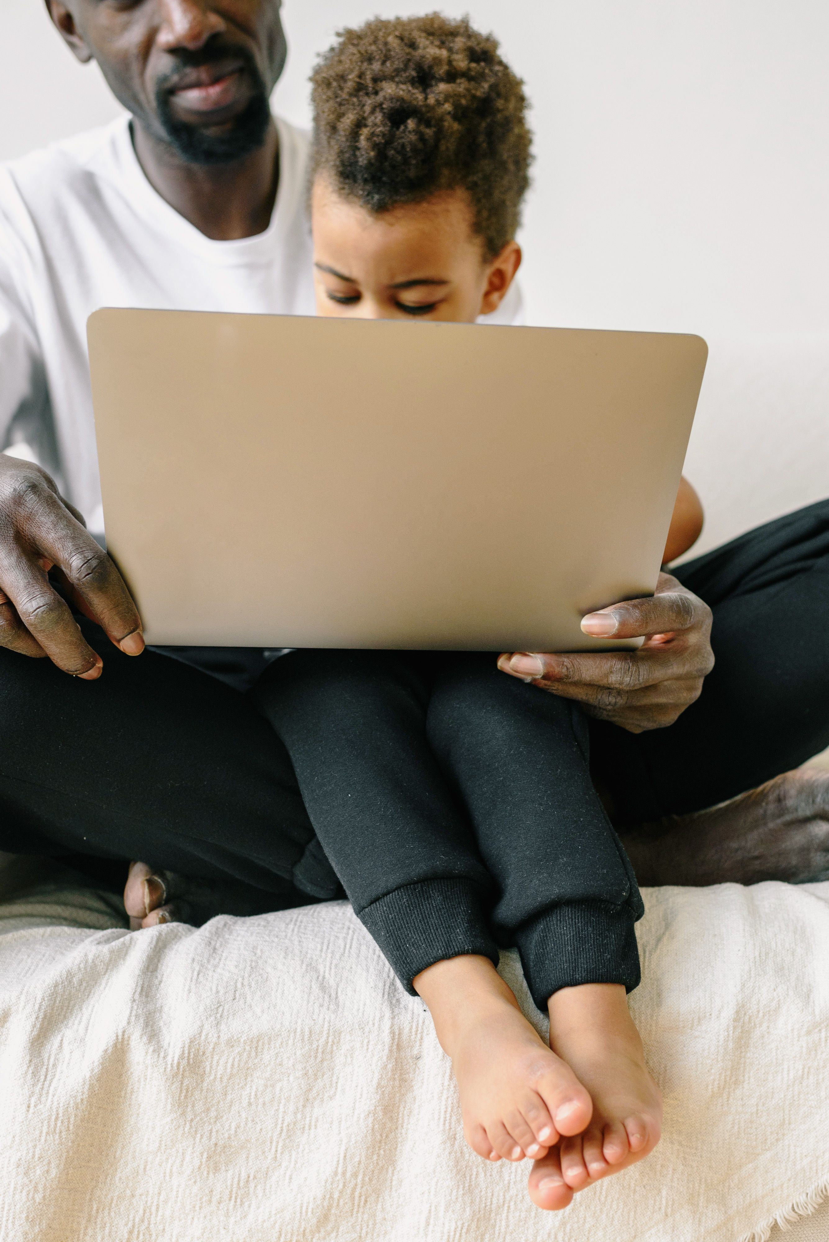 A father and son sharing a moment while using a laptop for online education, focus on bonding and technology.