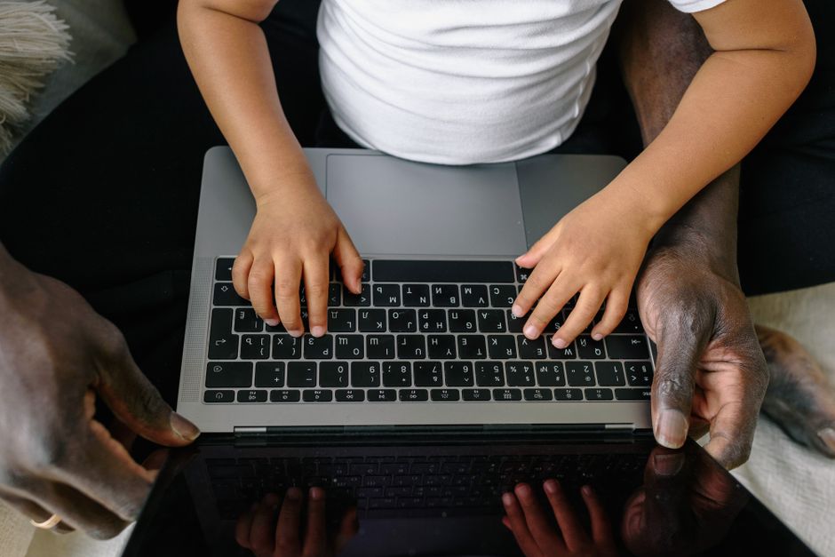 A child and adult using a laptop together, emphasizing learning and guidance.