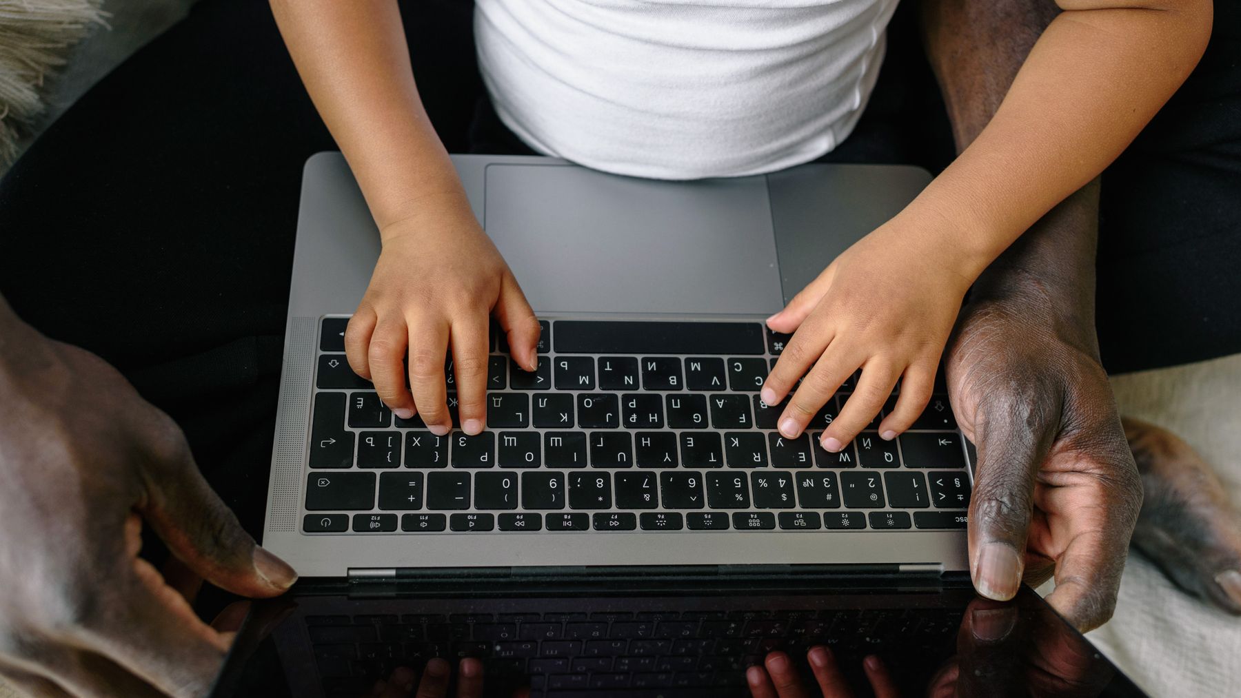 Adult and child using a laptop together in a supervised home setting