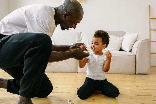Free Father and young son playing together in a cozy living room, showcasing love and family bond. Stock Photo