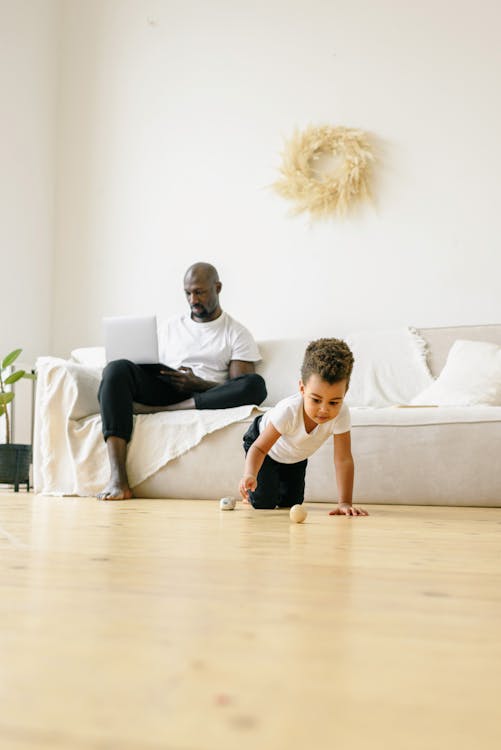 Boy in White Shirt Kneeling on Brown Wooden Floor