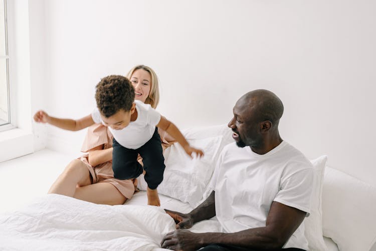 Happy Family With Child Playing In Bed