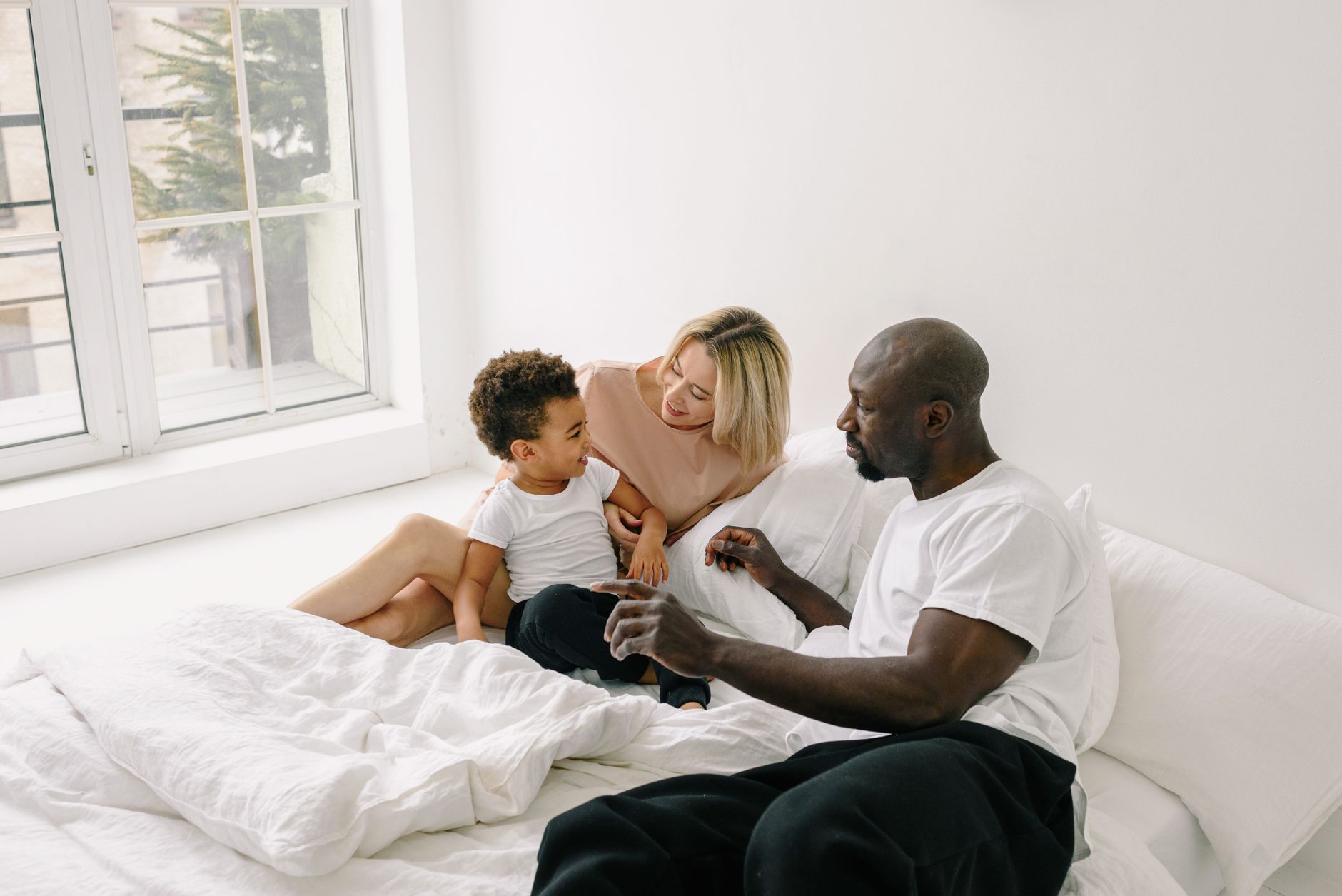A diverse family enjoying quality time together in a bright, cozy bedroom.