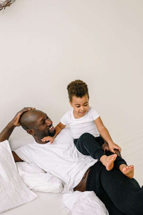 A Parent Playing with His Kid on the White Bed