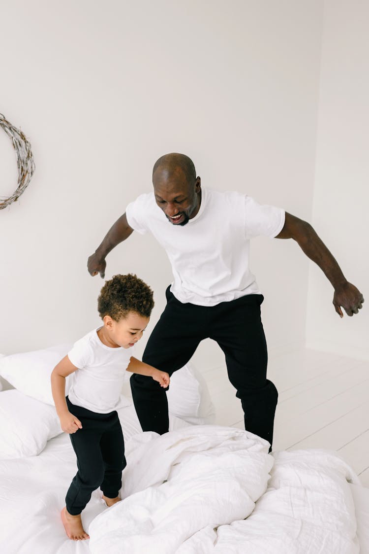 A Man And Boy Jumping Together In The Bed