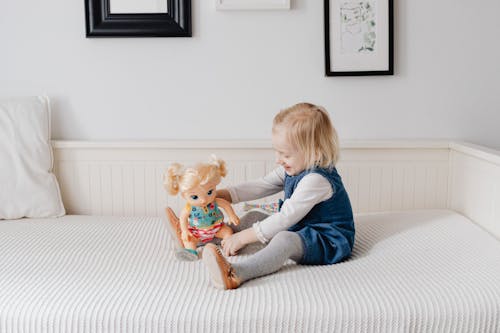 Free A Girl Playing a Doll on the Bed Stock Photo