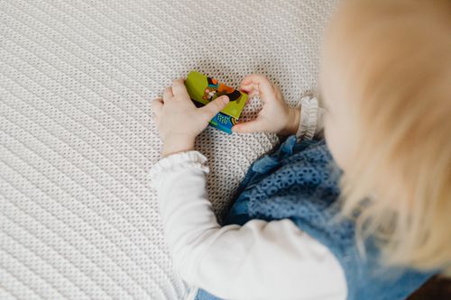Free A young child playing with vibrant toy blocks on a soft, textured blanket indoors. Stock Photo