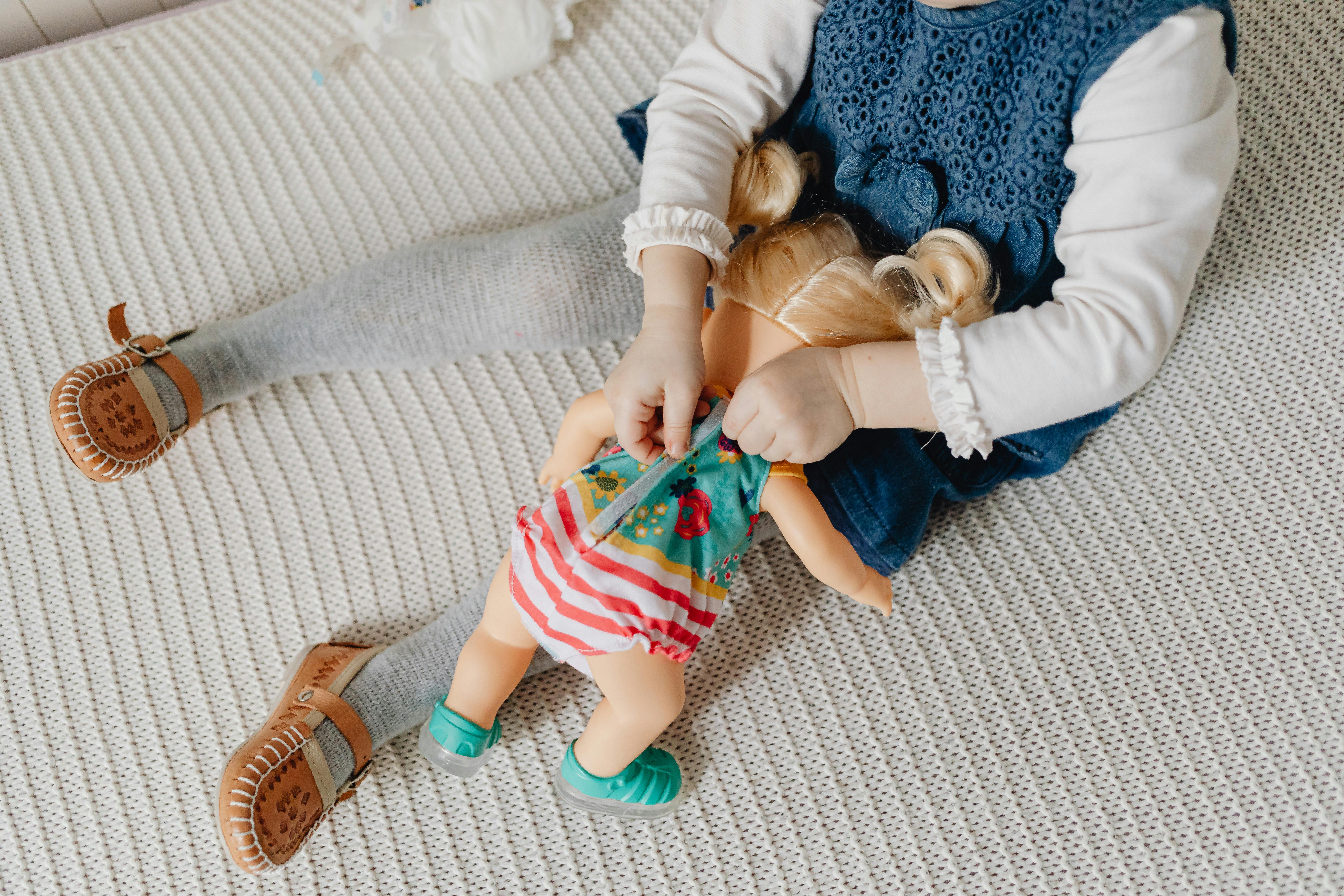 a girl dressing up her toy doll