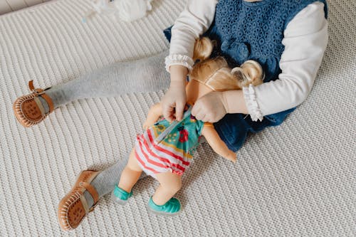 Free A Girl Dressing Up Her Toy Doll Stock Photo