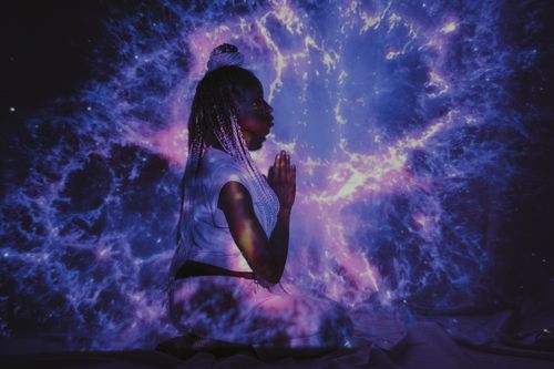Free A woman kneels in a galaxy projection, creating a mesmerizing cosmic backdrop. Stock Photo