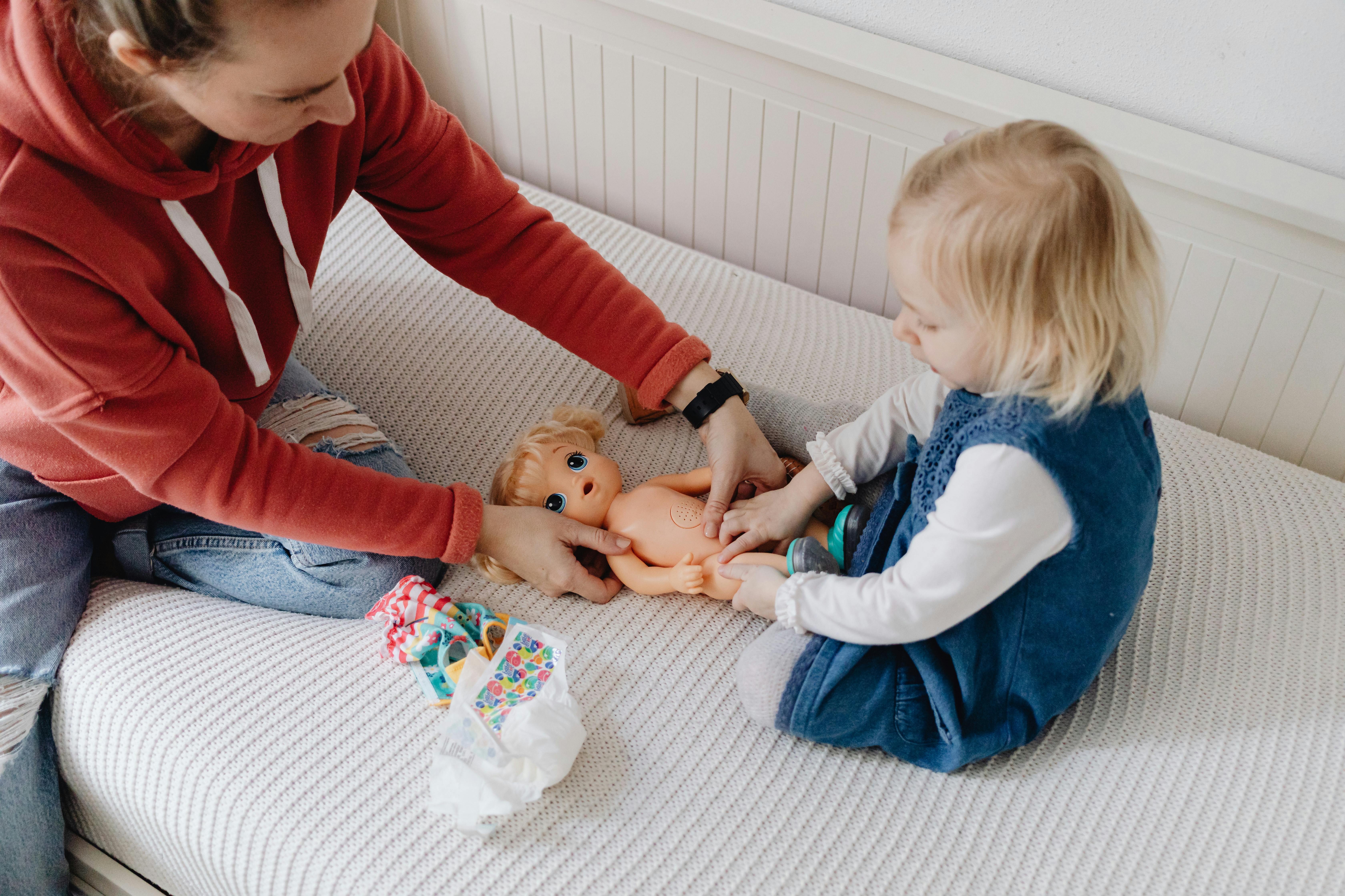 girl playing with a doll on the bed