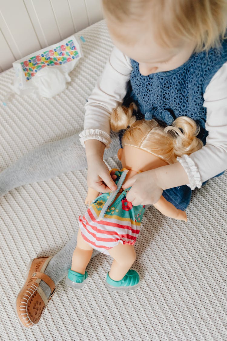 A Girl Sitting On The Bed Playing A Toy Doll