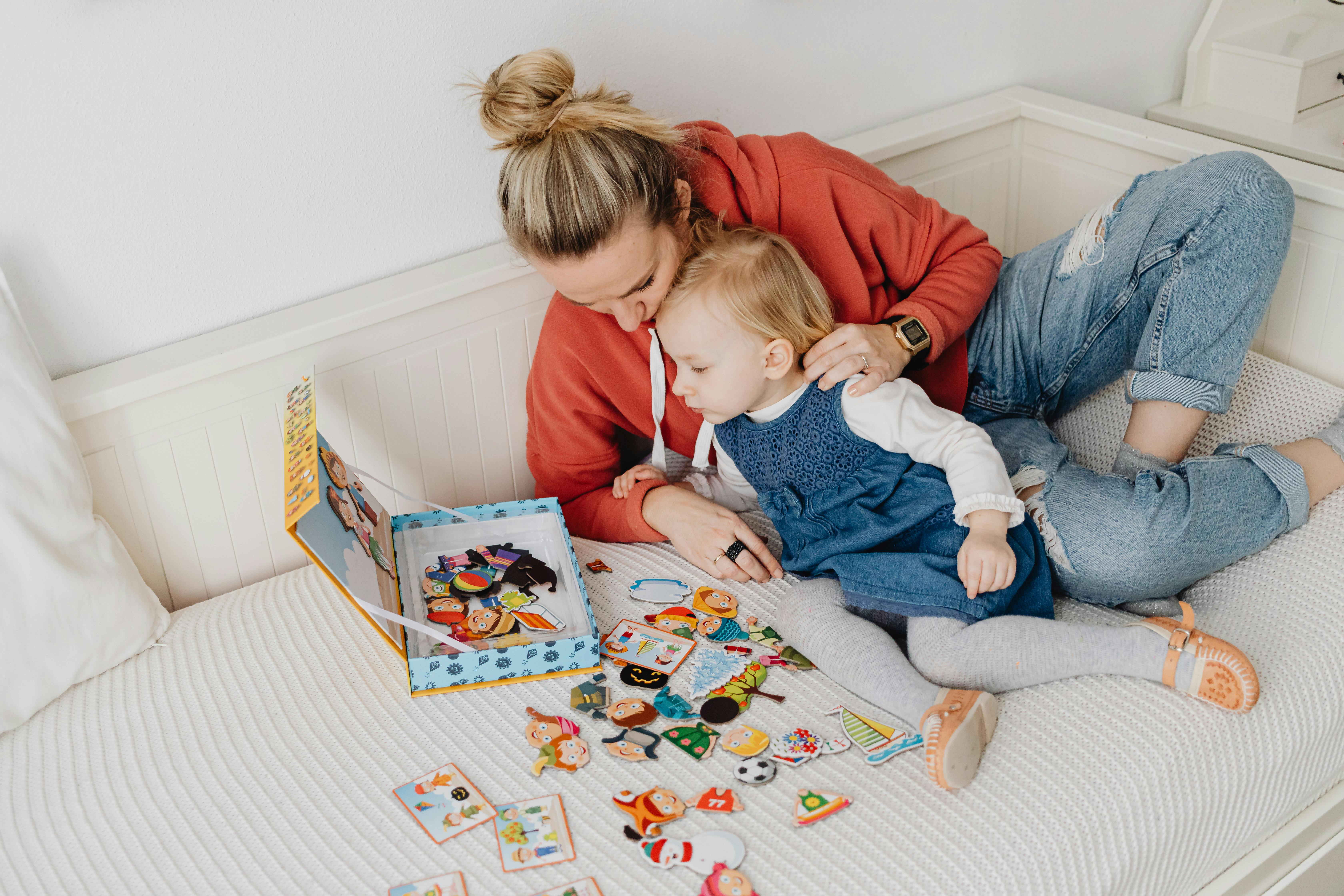 a mother and her child playing with toys on the bed