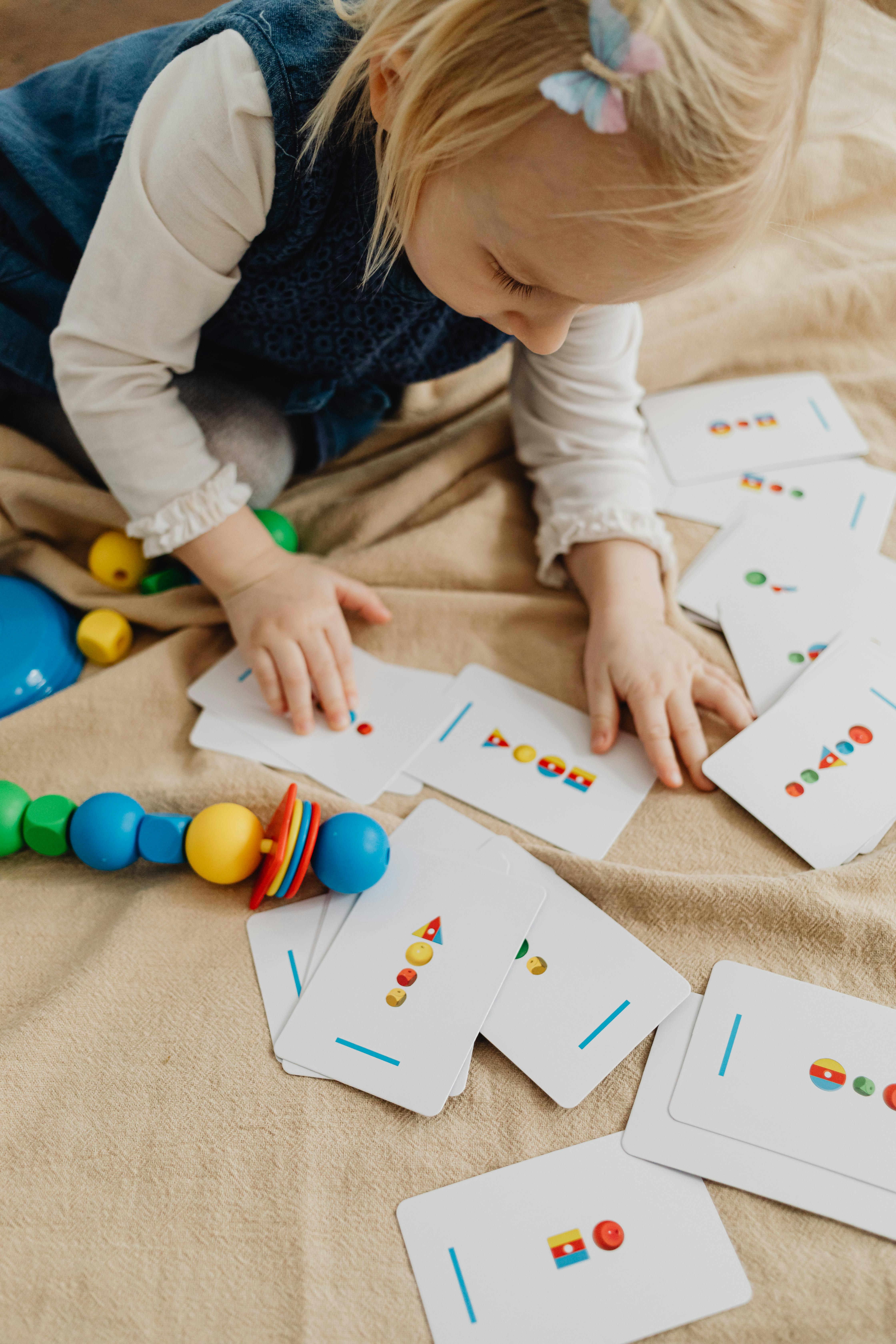 a child holding white cards with shapes