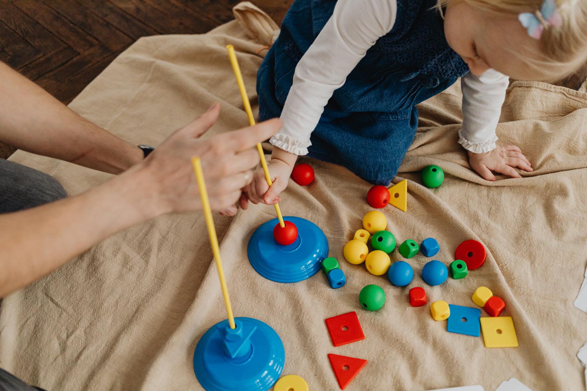 A child playing with educational toys, learning shapes and colors with a supervising adult.