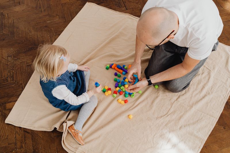 A young girl playing with toys alongside a therapist