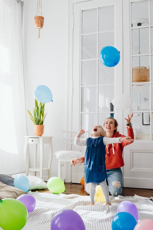 Free Mother and daughter having fun with balloons indoors, experiencing joy and happiness. Stock Photo