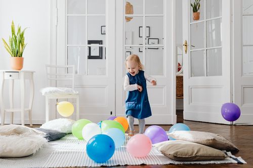 Free A cheerful young girl enjoying a playful moment with colorful balloons in a bright indoor setting. Stock Photo