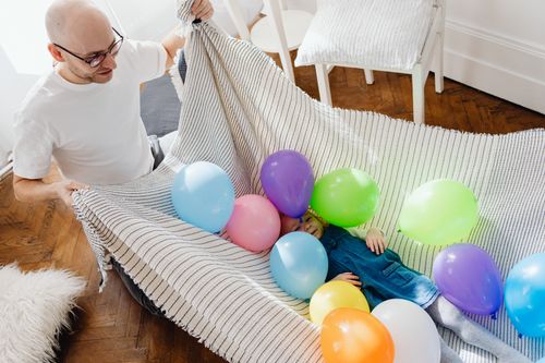Free A joyful moment inside with a father and daughter playing with colorful balloons. Stock Photo