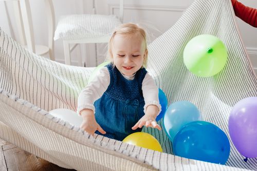 Free A cheerful young girl enjoying a playful moment with colorful balloons indoors. Stock Photo