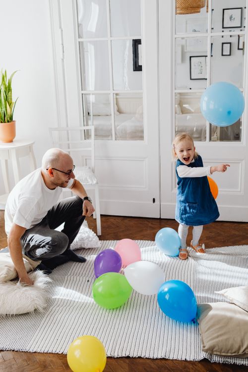 Free Happy father and daughter enjoying playtime with colorful balloons indoors. Capturing joy and family bonding moments. Stock Photo