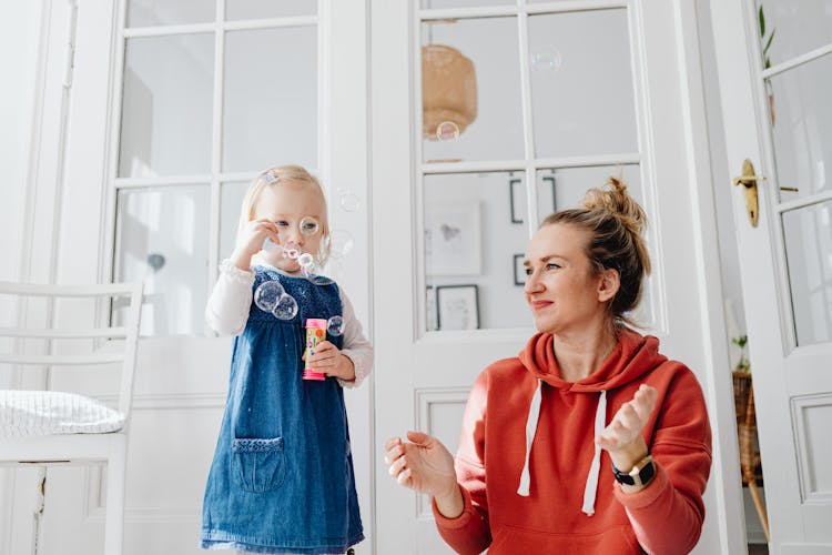 A Young Girl And Woman Playing Bubbles