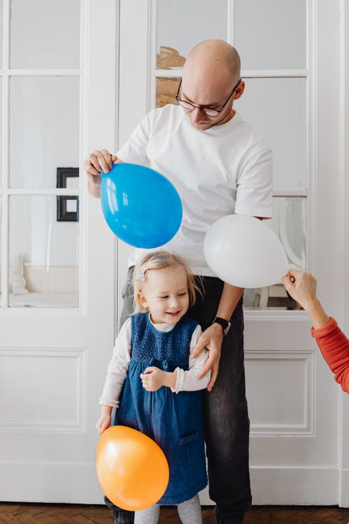 Free A happy father and daughter enjoy playing with colorful balloons indoors. Stock Photo