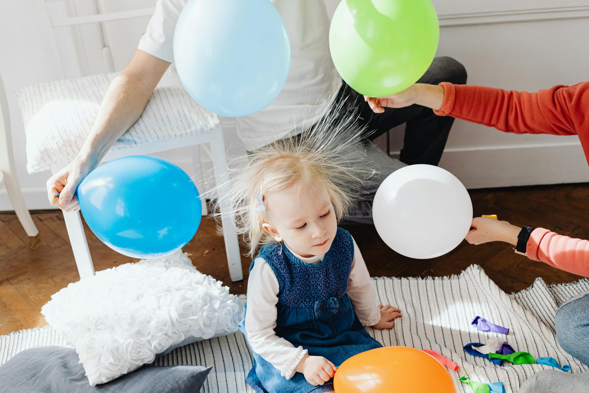 A joyful child enjoys a playful moment with colorful balloons, displaying static electricity hair indoors.